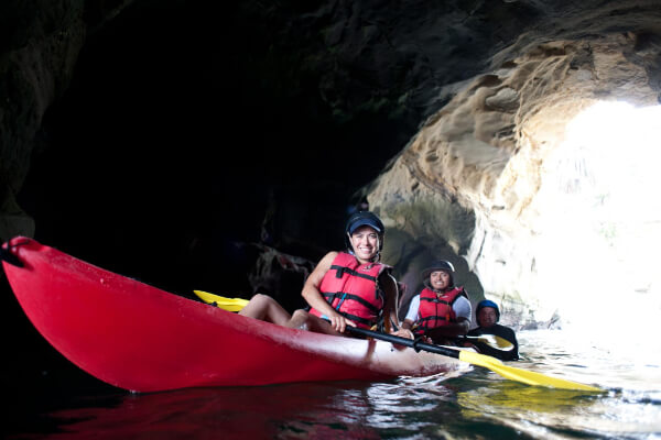 Two kayakers paddling along the La Jolla sea cave coastline