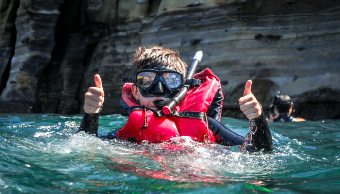 young snorkeler giving two thumbs off while exploring on a la jolla snorkel tour