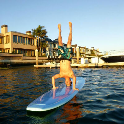 person doing a headstand on a stand up paddleboard rental
